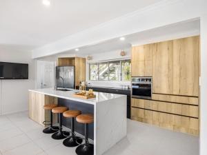 a kitchen with wooden cabinets and a counter with stools at Harborview Bliss 4BR Coastal Retreat w Pool in Gold Coast