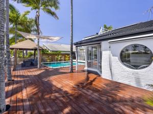 a house with a wooden deck with a swimming pool at Harborview Bliss 4BR Coastal Retreat w Pool in Gold Coast