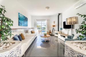 ein Wohnzimmer mit einem weißen Sofa und einem Fernseher in der Unterkunft Villa Paraíso in Poço Partido