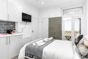 a white bedroom with a bed and a kitchen at Modern Studio Rooms in Zone 2 London in London