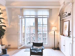 a living room with a chair and a large window at Spacious and beautiful flat in Mayfair, Berkeley St in London