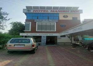 um carro estacionado em frente a um edifício de hotel em OYO Flagship Hotel Manish Inn em Aurangabad
