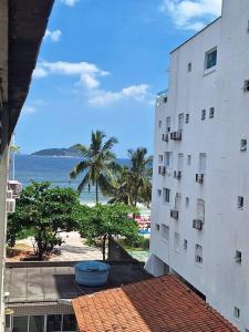 uma vista para um edifício e para o oceano a partir de uma varanda em Duplex pé na areia, praia do Tombo - Guarujá/SP. no Guarujá