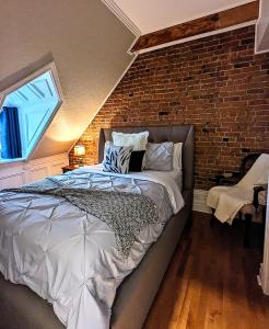 1 dormitorio con 1 cama con pared de ladrillo en Auberge J.A Moisan, en Quebec