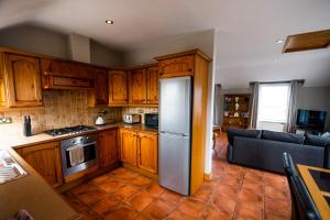 cocina con armarios de madera y nevera de acero inoxidable en 3 Fishery Cottages - 2 Bedroom house close to town en Bundoran