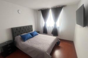 索加莫索的住宿－Apto cómodo en conjunto 1 piso parqueadero，一间卧室配有一张带蓝色枕头的床和一扇窗户。