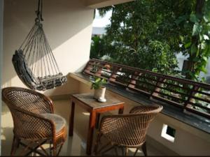 balkon z huśtawką, 2 krzesłami i stołem w obiekcie Mad about Coco Yoga & Beach Retreat w mieście Varkala