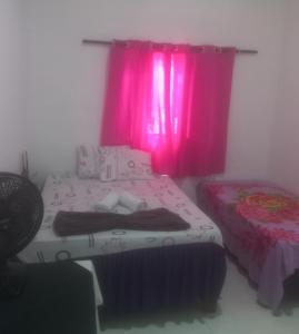 1 dormitorio con cama y cortina rosa en POUSADA CASA AMARELA, en Chapada dos Guimarães
