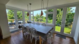 a dining room with a table and chairs and windows at Tantallon in Saint Just in Roseland