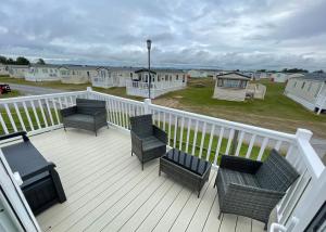 a deck with chairs and chairs on a house at Fairview Caravan Hire in Lossiemouth