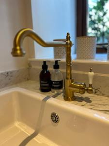a sink with a gold faucet and two bottles of soap at Converted coach house with parking in Pittenweem in Pittenweem