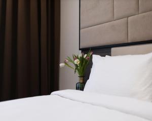 two beds with white sheets and a vase with flowers at Ribas Rooms Odesa in Odesa