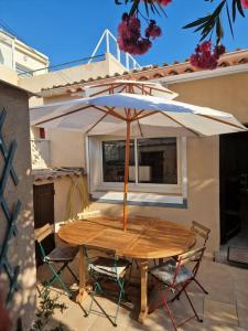 a wooden table and chairs with an umbrella on a patio at Charmante maison familiale vue sur mer in Marseille