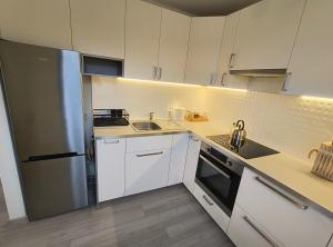 cocina con armarios blancos y nevera de acero inoxidable en Apartament Optymalny, en Tczew