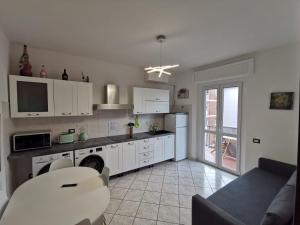 a kitchen with white cabinets and a living room at Cerro Flat in Cerro Maggiore