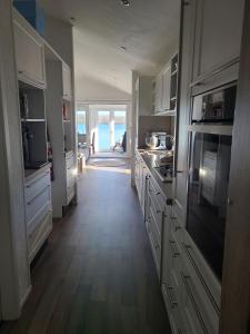 a kitchen with white cabinets and a long hallway at Vakantiepark Klein Vink - Boulevard 16 in Arcen