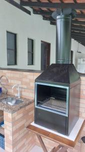 a stove in a kitchen with a sink at Maury Chalés Boiçucanga in São Sebastião