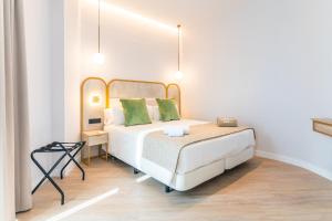 a bedroom with a white bed with green pillows at Hotel Málaga Vibes in Málaga