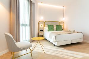 a hotel room with a bed and a chair at Hotel Málaga Vibes in Málaga