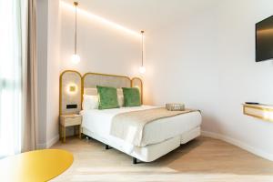a bedroom with a white bed with green pillows at Hotel Málaga Vibes in Málaga