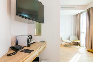 a hotel room with a desk with a television on a wall at Hotel Málaga Vibes in Málaga