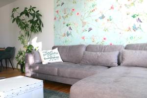 ein Wohnzimmer mit einem grauen Sofa und einer Blumenwand in der Unterkunft Traunseeresidenzen in Gmunden