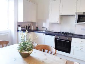 a kitchen with white cabinets and a table with a plant at 18 The Circus Apartment in Bath