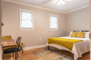 1 dormitorio con 1 cama, escritorio y 2 ventanas en Maine Avenue- Downtown Southern Pines, en Southern Pines