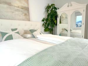1 dormitorio con 2 camas blancas y espejo en Traunseeresidenzen en Gmunden