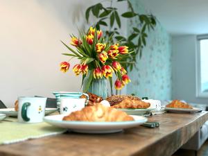 einen Tisch mit Teller mit Lebensmitteln und eine Vase mit Blumen in der Unterkunft Traunseeresidenzen in Gmunden