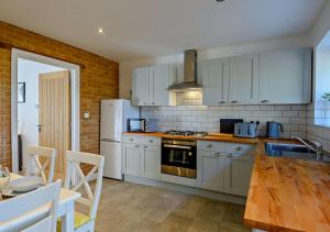 a kitchen with white appliances and a wooden table at No 6 Deer Glade in Sparham