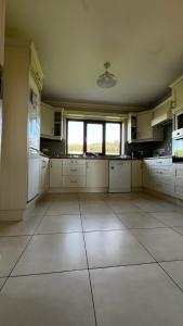 a large kitchen with white cabinets and a window at BARR AN CHNOIC HOLIDAY LETTINGS in Tipperary