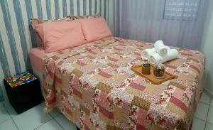 a bed with a quilt and a tray with a tissue at Apartamento próximo a praia. in Laguna