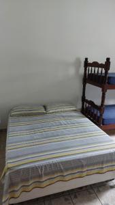 a bed in a bedroom with a striped blanket at Maury Chalés Boiçucanga in São Sebastião