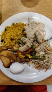 um prato branco de alimentos com arroz e carne em N.K. Residency em Guwahati