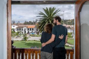 a man and a woman standing on a balcony looking out a window at Casona Del Rosario - Plaza de Armas in Chachapoyas