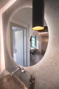 a bathroom with a round mirror over a sink at MAKRIS Papigo Luxury suites in Papigko