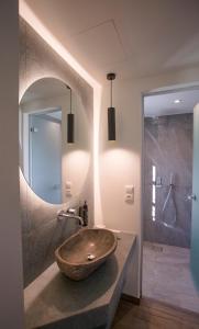 a bathroom with a stone sink and a mirror at MAKRIS Papigo Luxury suites in Papigko