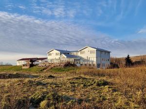 una gran casa blanca en la cima de un campo en Gauksmýri guesthouse en Hvammstangi