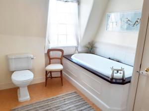 a bathroom with a tub and a toilet and a chair at 18 The Circus Apartment in Bath