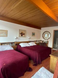 1 dormitorio con 2 camas con sábanas rojas y techo de madera en Hosteria La Chacra en Esquel
