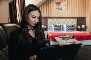 Una donna seduta davanti a un portatile in una stanza d'albergo di Business Hotel Plovdiv a Plovdiv
