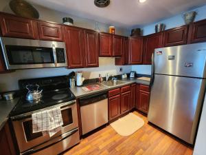 uma cozinha com armários de madeira e electrodomésticos de aço inoxidável em Beautiful Apt, Woffice Area 2br, Long Term em Elkins Park