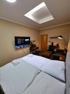 um quarto com uma cama branca e uma televisão de ecrã plano em Aparthotel Olympland em Trutnov