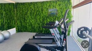 a gym with a green wall with a bike at Flat Makia Beach Experience Muro Alto in Porto De Galinhas