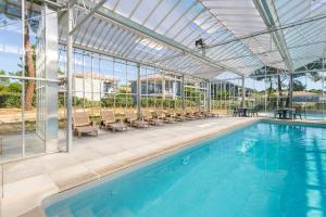 an indoor swimming pool with chairs and a large building at Lagrange Vacances L'Estuaire in Le Verdon-sur-Mer