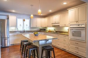 a kitchen with white cabinets and a island with bar stools at Sleeps 7- Whispering Pines Lake Front 