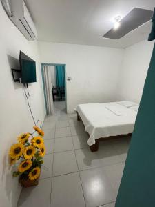 Zimmer mit einem Bett und einer Vase von Sonnenblumen in der Unterkunft Tourquesa Excellent WiFi Private in Liberia