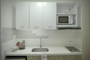 a kitchen with white cabinets and a sink and a microwave at Apartamento completo centro de Bogotá in Bogotá