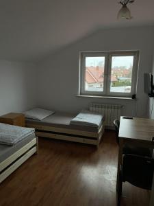 a room with two beds and a window at Noclegi Pracownicze LAZUR in Ciechanów